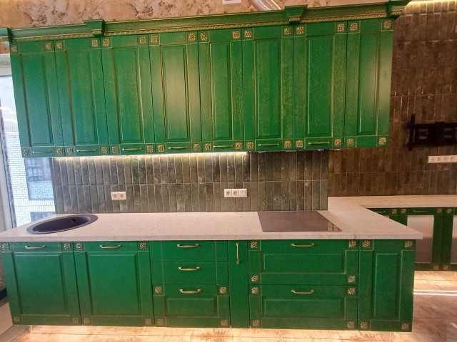 Белая кварцевая столешница в контрасте с зелеными фасадами