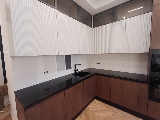 Глянцевая элегантность черной столешницы в двухцветной кухне