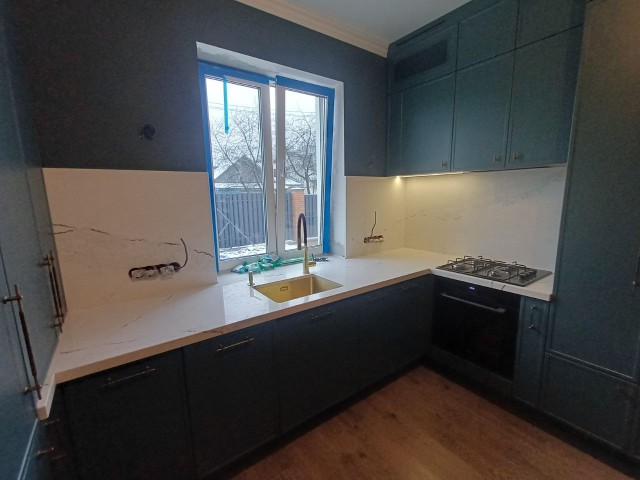 Белая столешница с прожилками в контрастном дуэте с темными фасадами